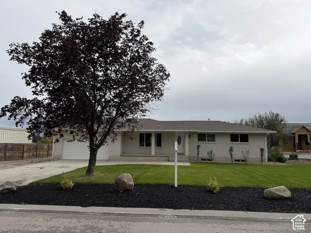 Single-story residence featuring a two-car garage, established front yard landscaping, and a paved driveway