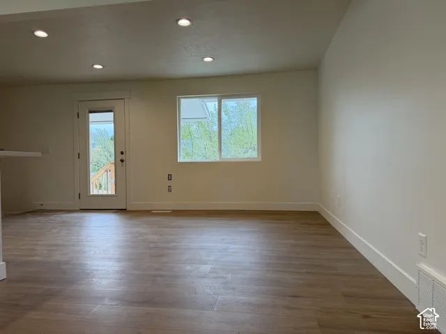 Recessed ceiling lighting, wood-finish flooring, white walls, and a glass-paneled exterior door
