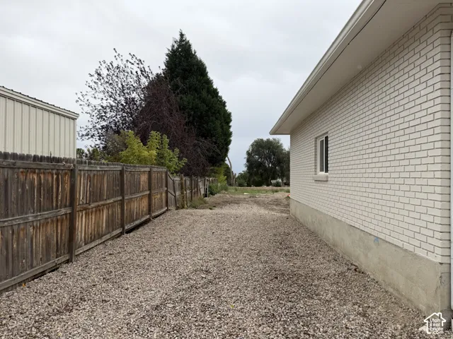 White brick exterior with a single window, gravel ground cover, and a wood fence