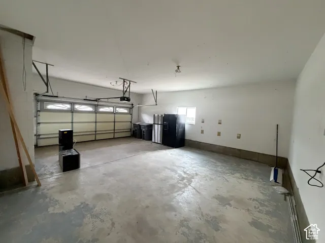 Spacious garage with an overhead door, automatic opener, concrete flooring, and an integrated window