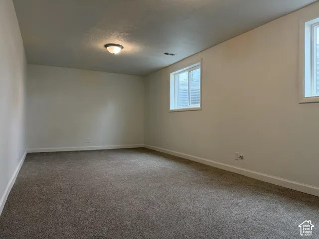 Recessed windows providing natural light, overhead flush mount lighting, textured ceilings, white painted walls, and gray carpeting