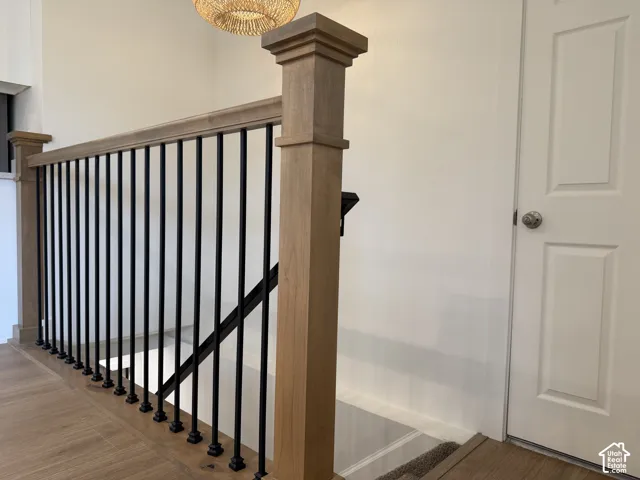 Wood-finish flooring, staircase with metal balusters, and a solid white paneled door
