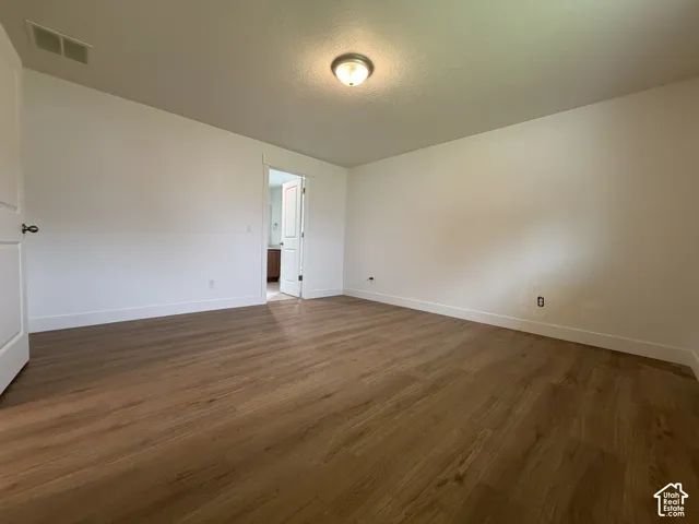 Spacious room featuring wood-finish flooring, white walls, and a ceiling-mounted light fixture