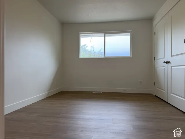 Neutral wall finishes, wood-finish flooring, white trim, and a double-panel closet door