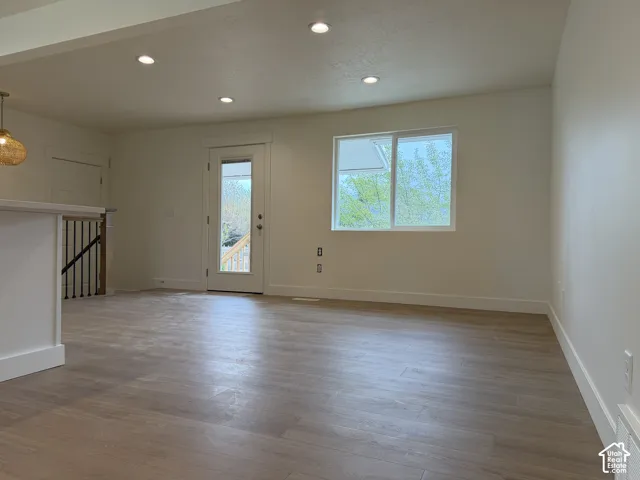 Wood-finish flooring, recessed lighting, white baseboards, a door with a glass panel, and a window with white trim