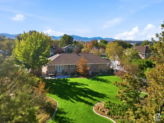 Spacious backyard featuring a manicured lawn, established landscaping, and mature trees