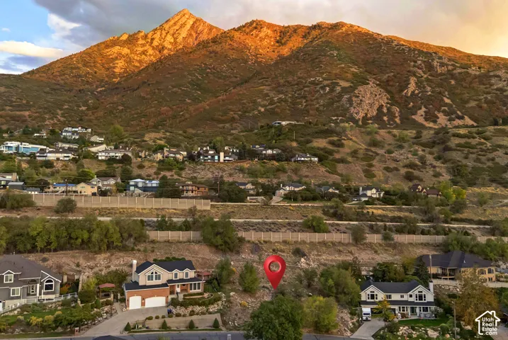 Mountain backdrop, residential hillside setting, and multiple properties with varied architectural styles