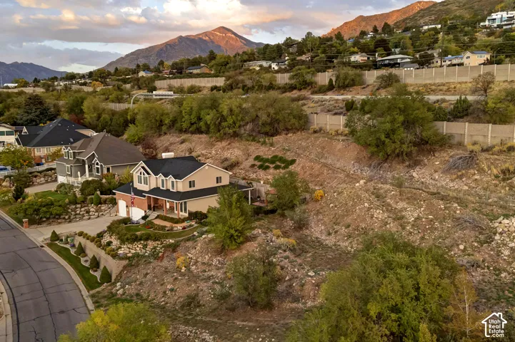 Mountainous backdrop, residential neighborhood, paved road, multi-story residence, attached garage