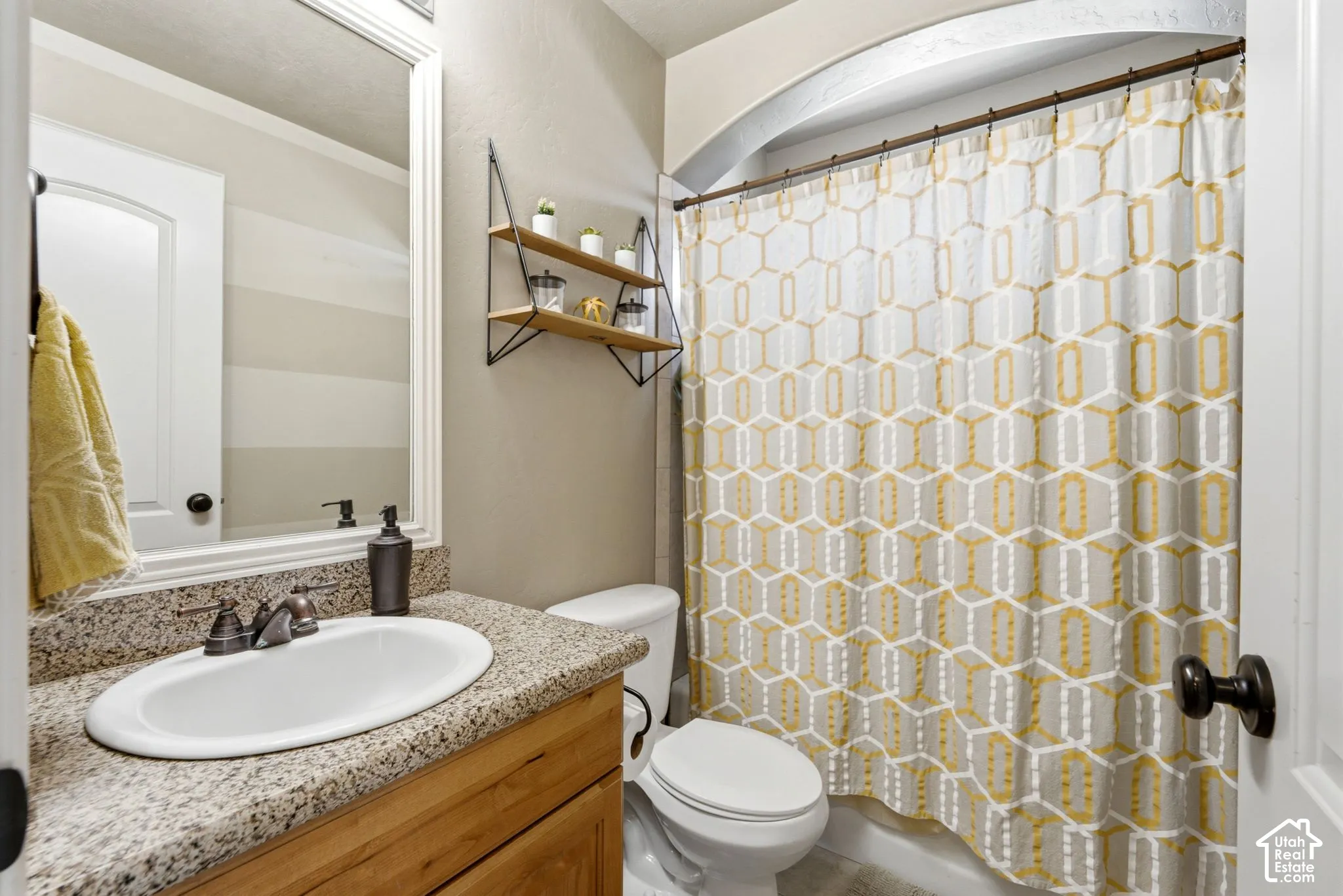 Bathroom featuring a vanity with a light-toned stone countertop, integrated oval sink, and wood-finish cabinetry