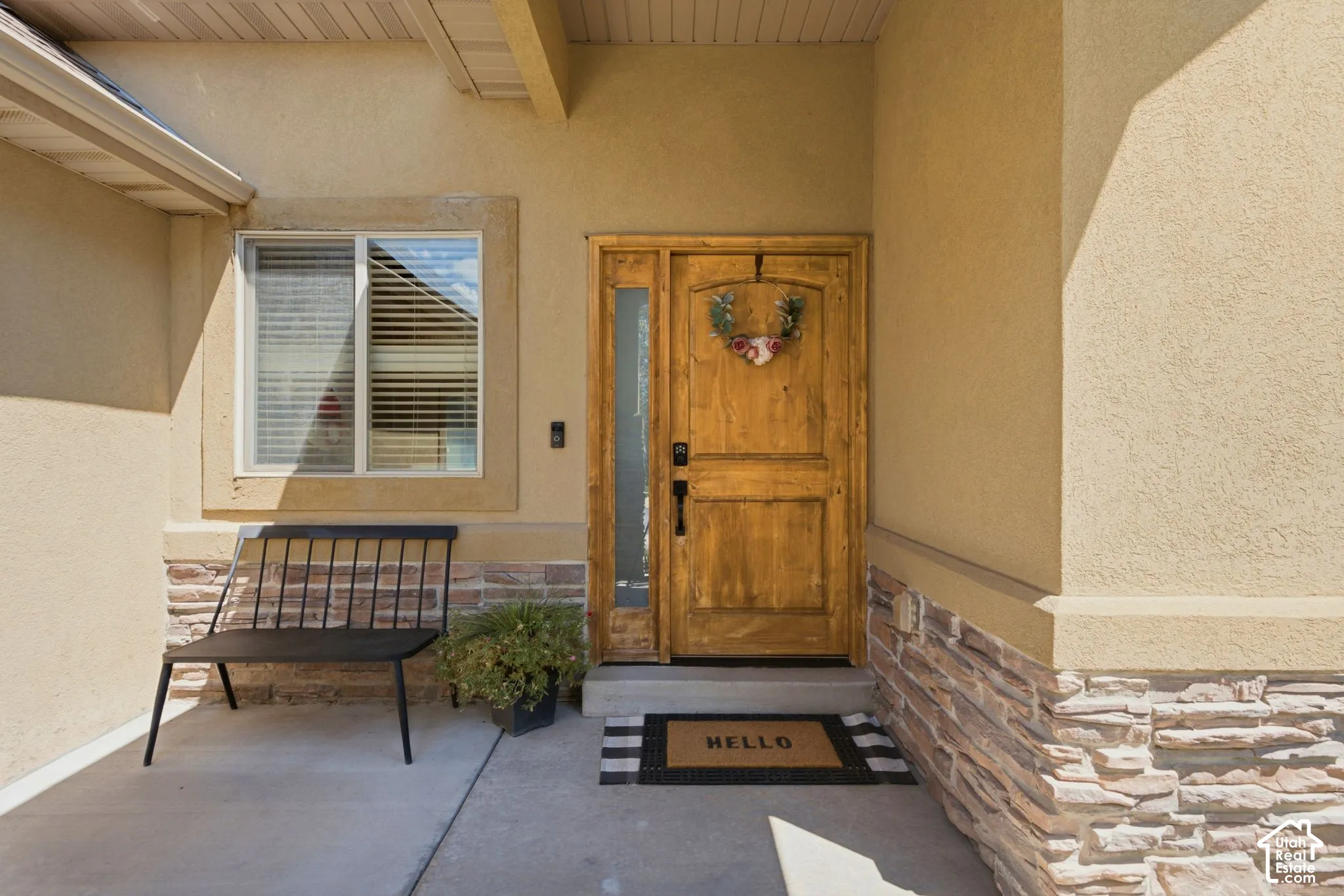 Front entrance featuring a wood-panel door with sidelight, complemented by stucco siding and a stacked stone facade