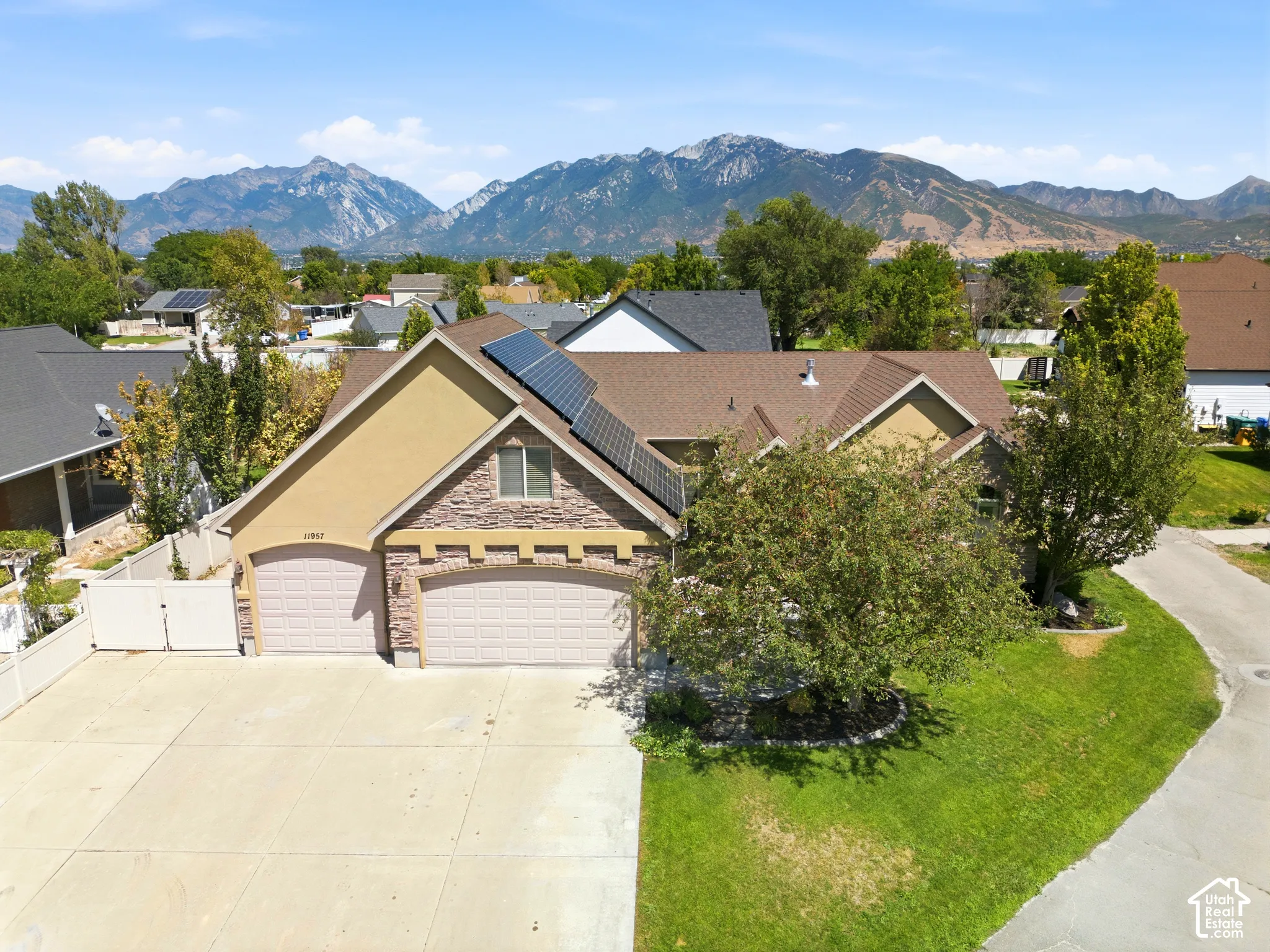 Mountain backdrop, attached two-car garage, stone and stucco exterior, solar panel installation, paved driveway