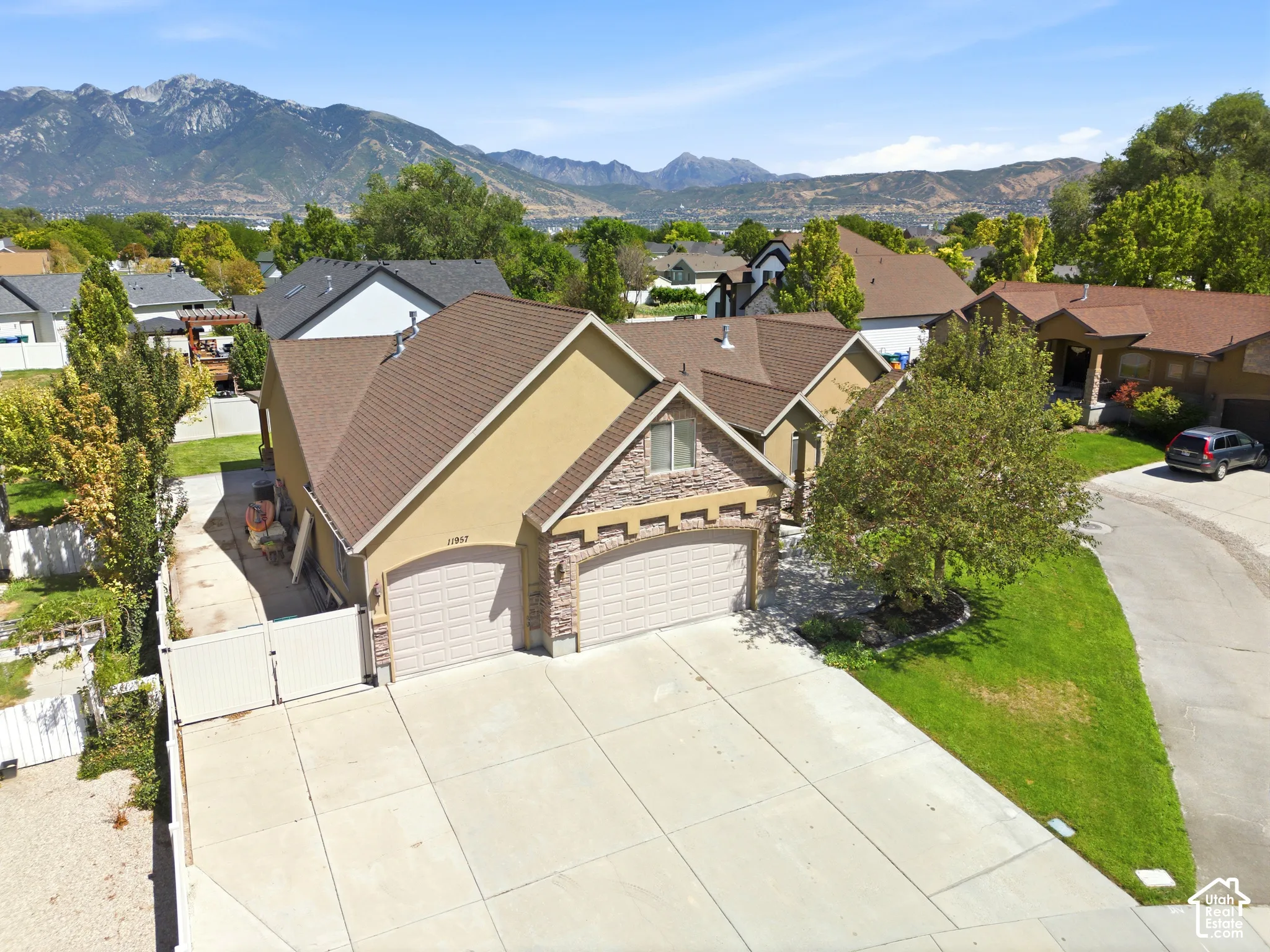 Stucco and stone exterior with a two-car garage, concrete driveway, and a gated side yard