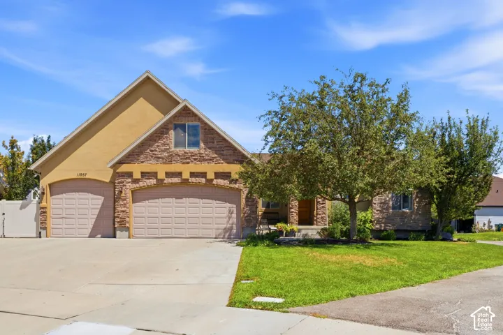 Stucco and stone facade home featuring a prominent pitched roofline and arched stone detailing over the garage