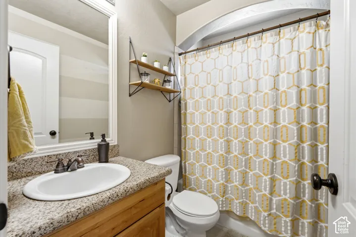 Bathroom featuring a vanity with a light-toned stone countertop, integrated oval sink, and wood-finish cabinetry
