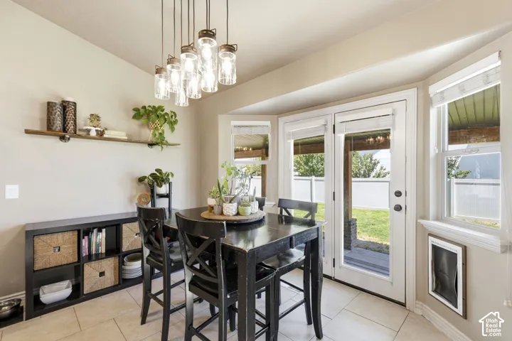 Dining area featuring a modern multi-pendant light fixture, bay windows, and French doors leading to the exterior