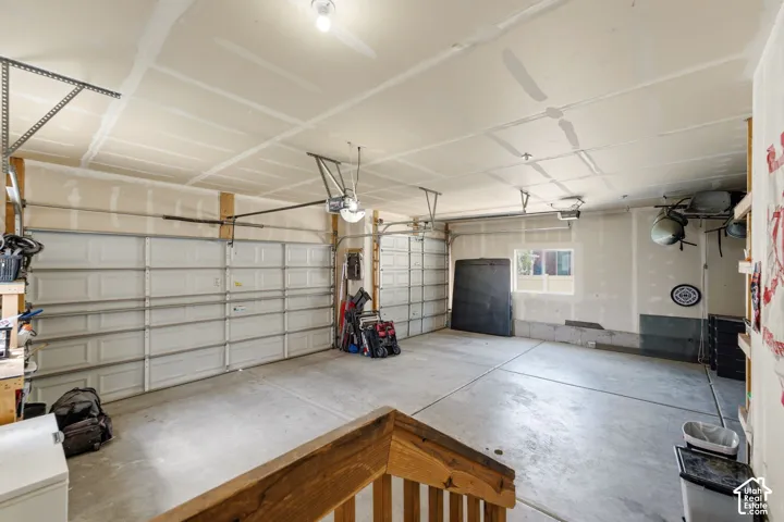 Spacious garage featuring two overhead doors, concrete flooring, exposed ceiling joists, and a single window
