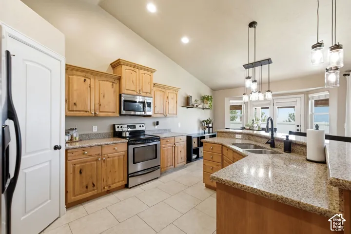 Vaulted kitchen featuring light wood cabinetry, stainless steel appliances, granite countertops, and tile flooring