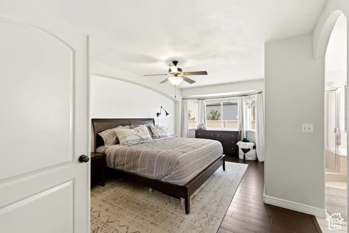 Room featuring dark wood-finish flooring, a bay window with white trim, and a ceiling fan