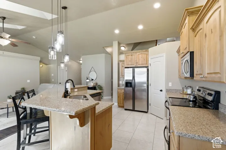 Kitchen featuring light wood cabinetry, speckled countertops, stainless steel appliances, and tile flooring