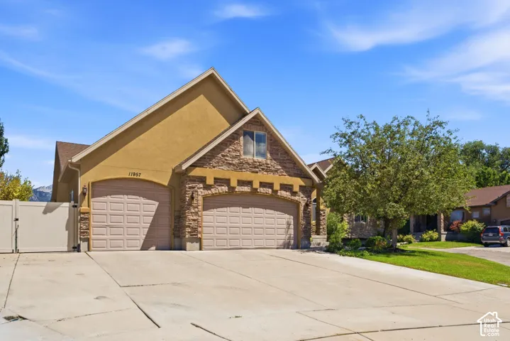 Stucco and stone facade home featuring a two-car garage with arched doors, an additional one-car garage, and a concrete driveway