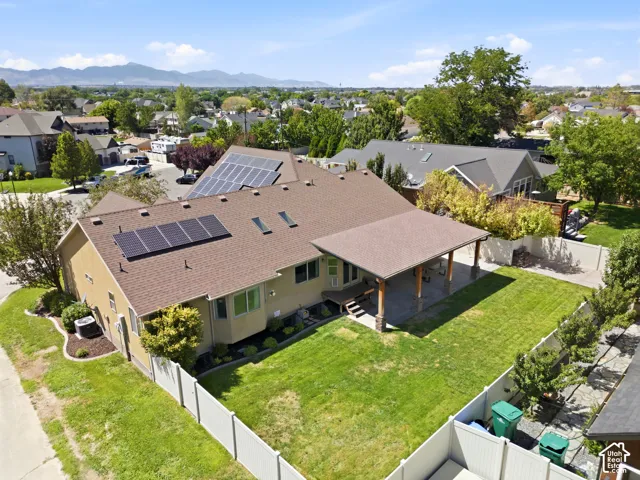 Expansive green lawn with a covered patio, multiple solar panel arrays, and a white perimeter fence