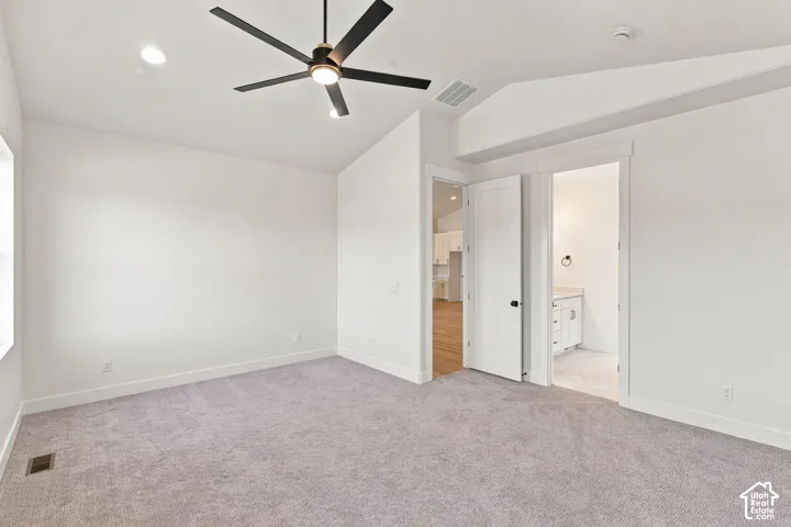 White walls, vaulted ceiling, recessed lighting, and a dark-toned ceiling fan