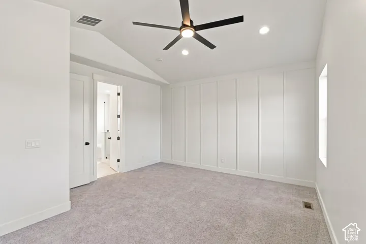 Vaulted ceiling with recessed lighting and a modern ceiling fan, accent wall featuring vertical paneling, plush carpeting, and contemporary doors with dark hardware