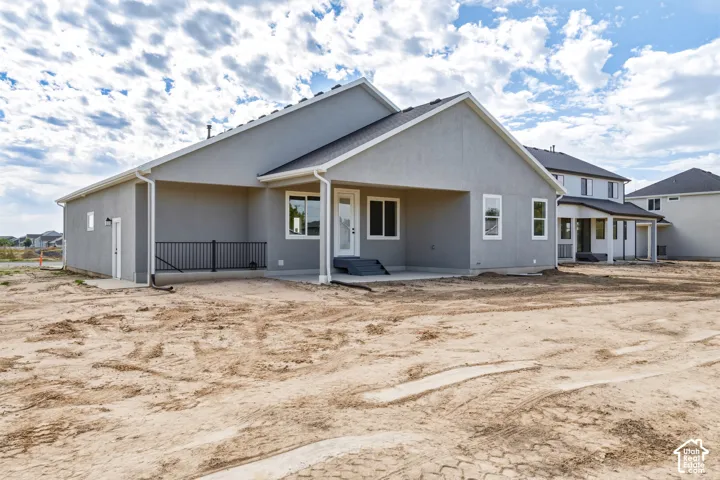 Stucco exterior with white trim, dark shingle roof, and a covered concrete patio