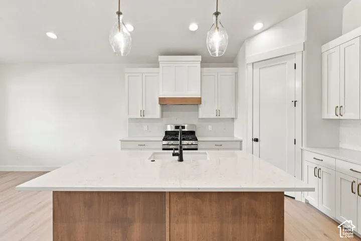 Kitchen featuring a center island with a stone countertop, wood-finish base, and integrated sink with a black faucet