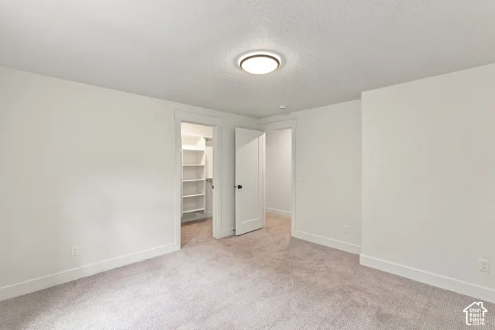 Neutral-toned carpeting, white walls, and a flush-mount ceiling light fixture