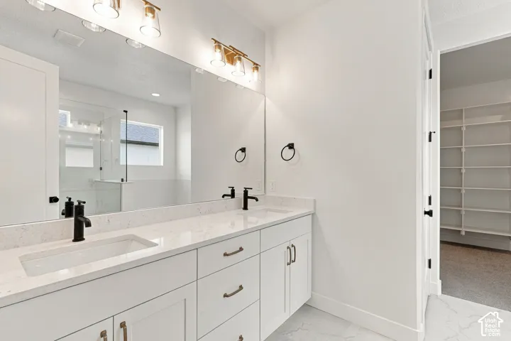 Dual sink vanity with quartz countertops, matte black fixtures, and gold-finish lighting