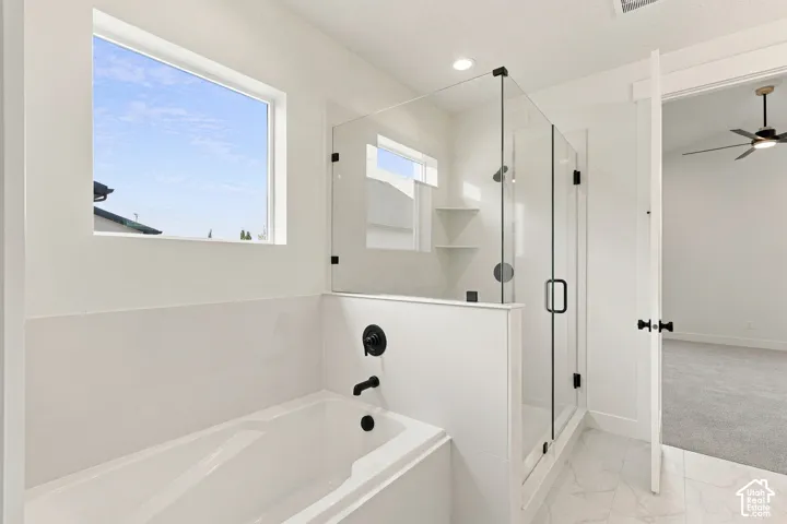 Built-in soaking tub, glass-enclosed shower with matte black fixtures, integrated shower shelving, and large format floor tiling