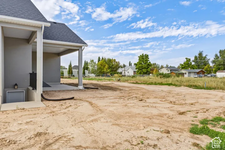 Covered patio with concrete flooring, stucco exterior, and a dark shingle roof