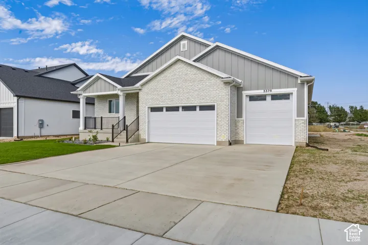 White brick facade with gray siding, a covered entryway, and a two-car garage