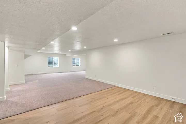 Recessed lighting illuminates the expansive space, featuring both wood-finish flooring and patterned carpeting