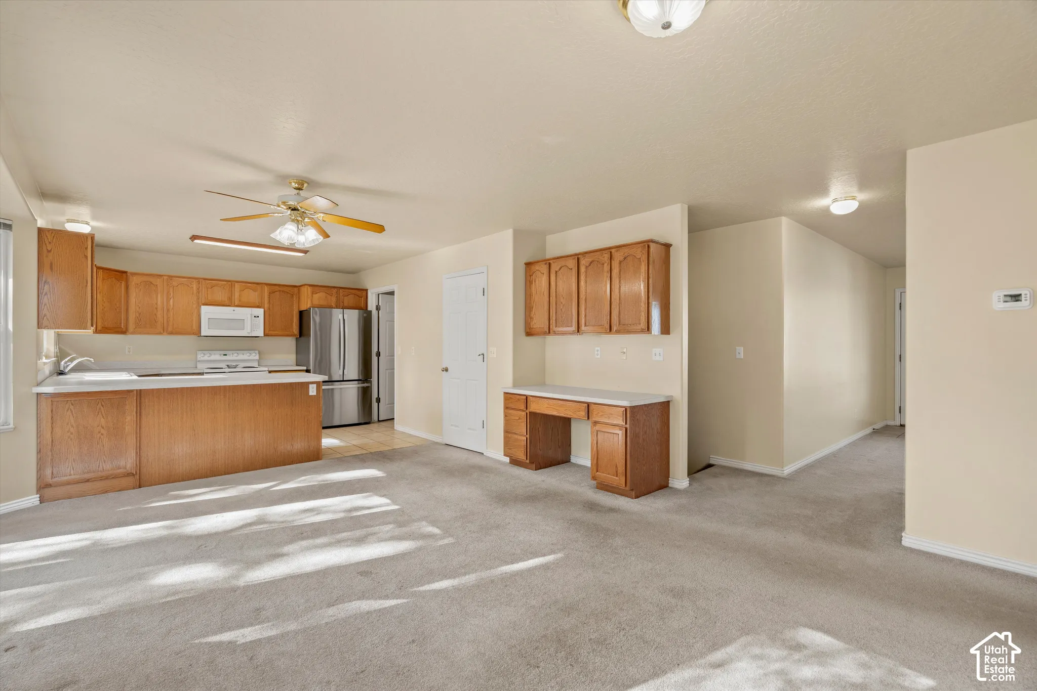 Kitchen featuring wood-finish cabinetry, white appliances, and a central island