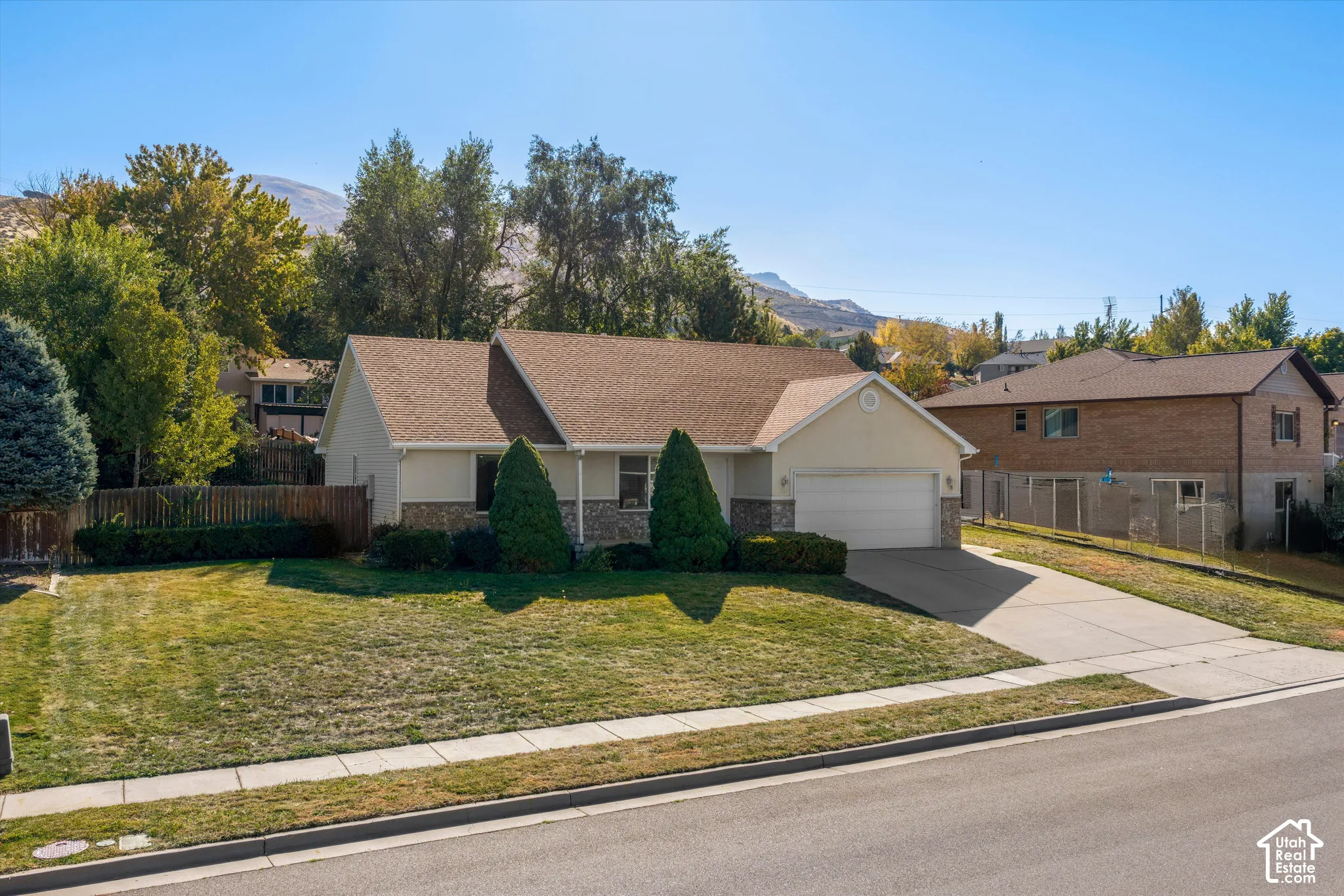 Single-level residence with an attached garage, featuring a shingle roof and a concrete driveway