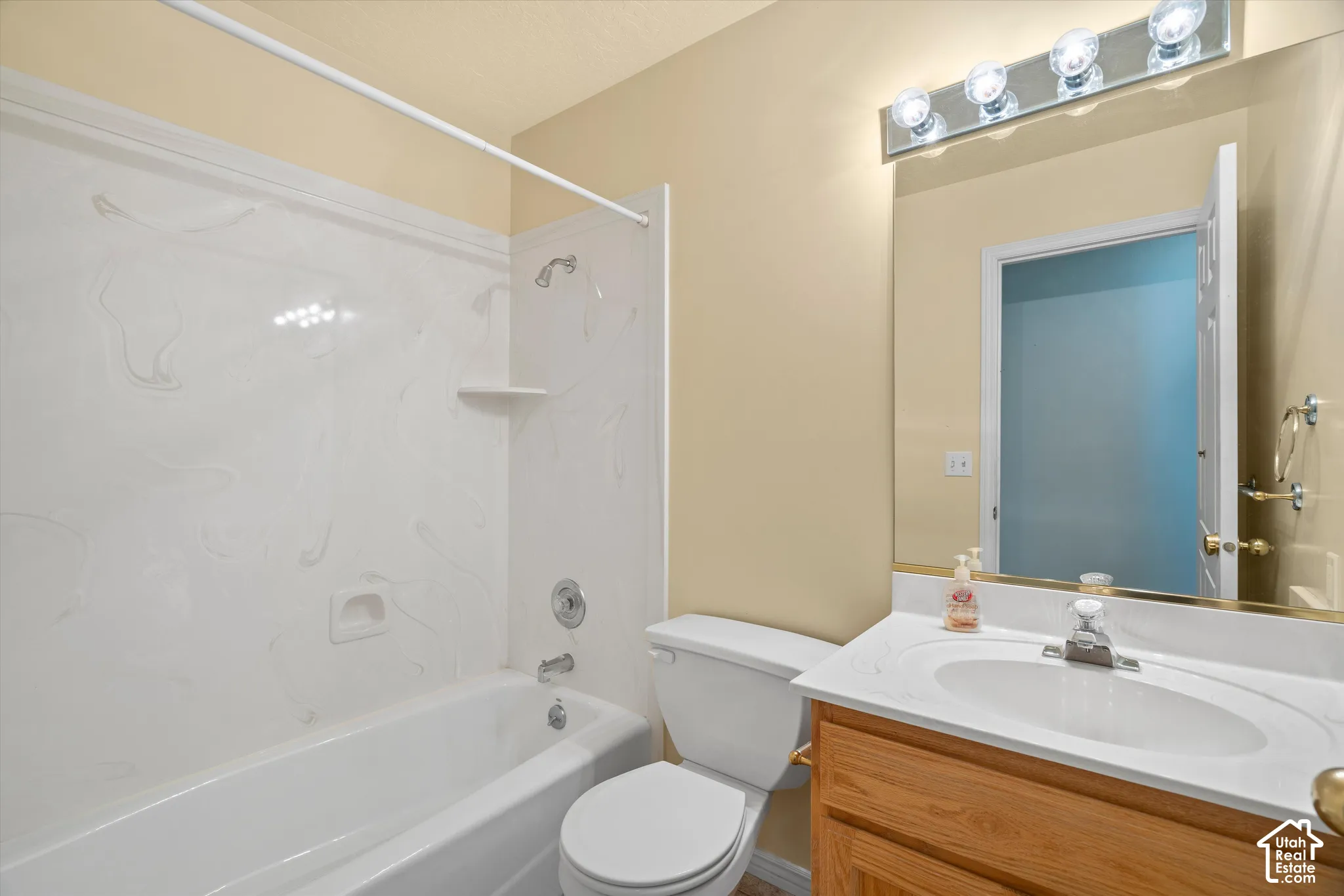 Full bathroom featuring a white bathtub and shower surround, a vanity with a white countertop and integrated sink, and a mirrored wall