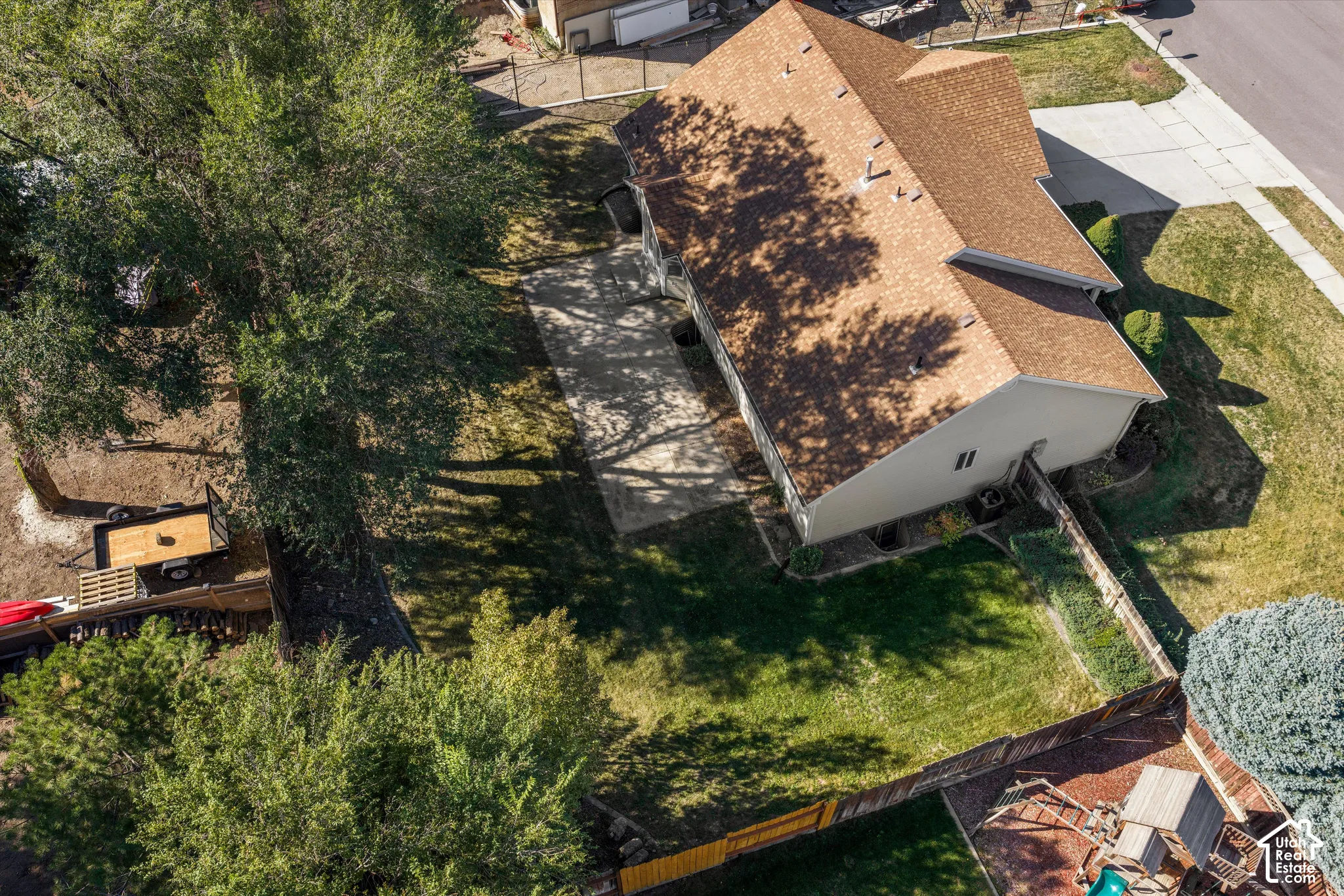 Asphalt shingle roof, paved driveway, expansive grassy yard, mature trees, wood fence