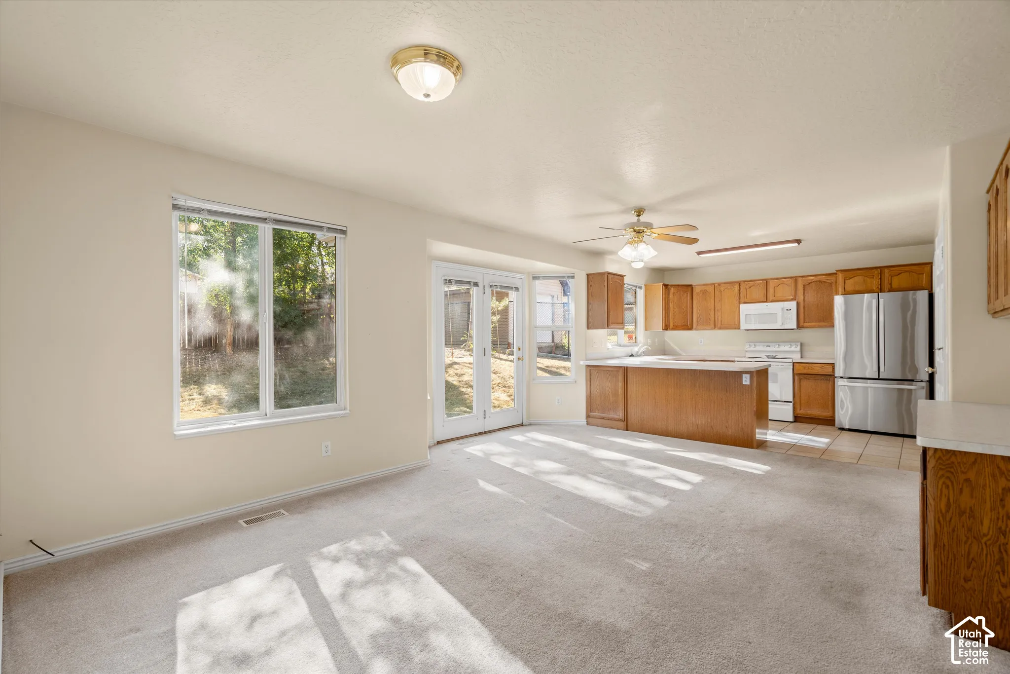 Recessed kitchen with wood cabinetry, stainless steel appliances, and tile flooring