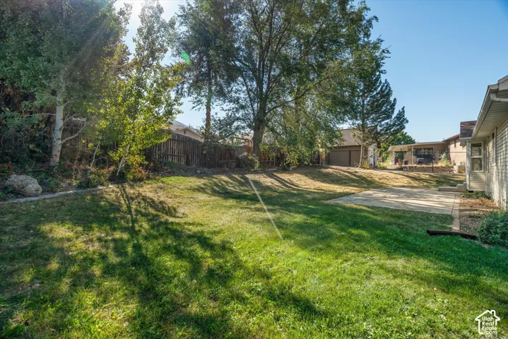 Expansive lawn area with mature trees, established landscaping, and a concrete patio