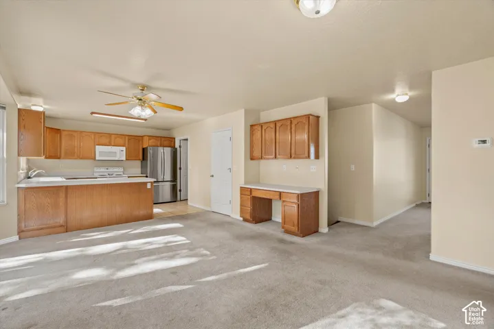 Kitchen featuring wood-finish cabinetry, white appliances, and a central island