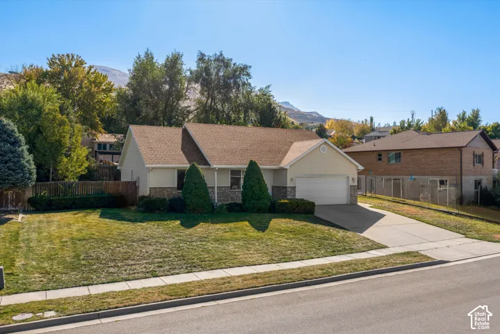 Single-level residence with an attached garage, featuring a shingle roof and a concrete driveway