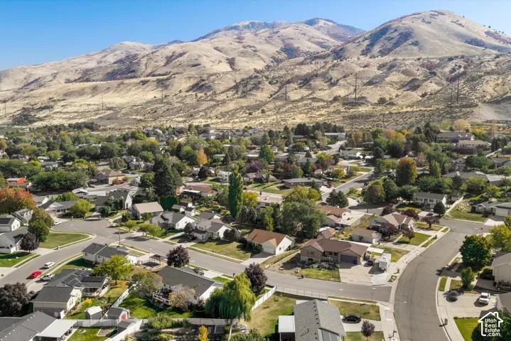 Expansive neighborhood setting with mature trees and paved streets, surrounded by significant mountain topography