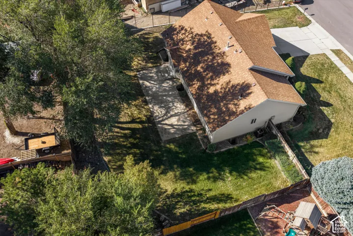 Asphalt shingle roof, paved driveway, expansive grassy yard, mature trees, wood fence