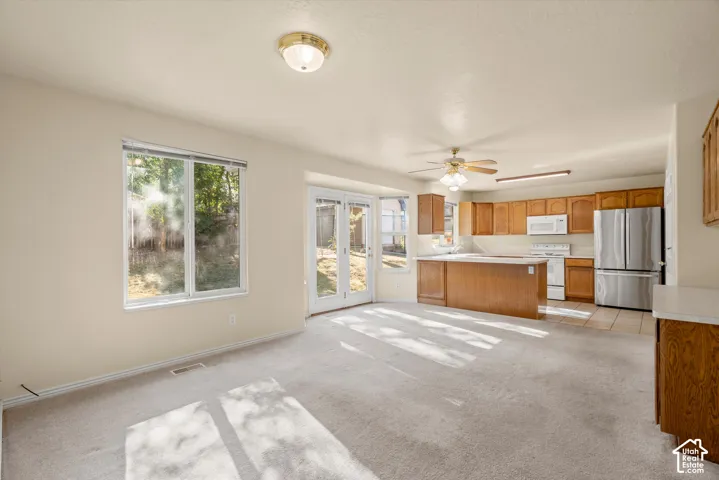 Recessed kitchen with wood cabinetry, stainless steel appliances, and tile flooring