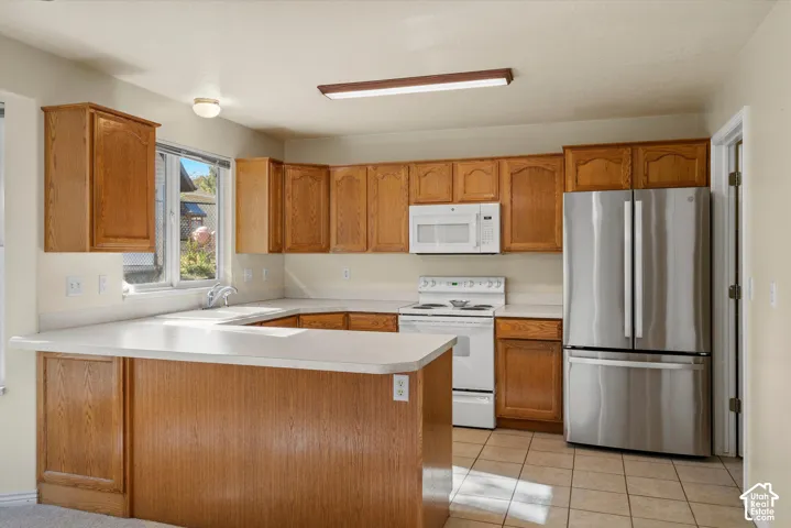 U-shaped kitchen featuring wood cabinetry, light-toned countertops, and tile flooring