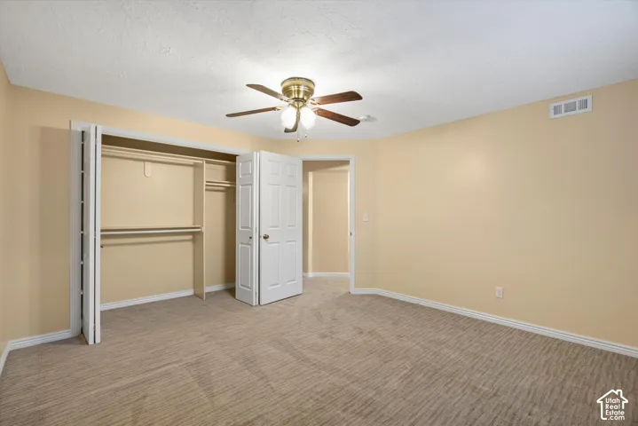Spacious bedroom with wood-finish flooring, a ceiling fan with integrated lighting, and a large walk-in closet with dual sliding doors and interior shelving