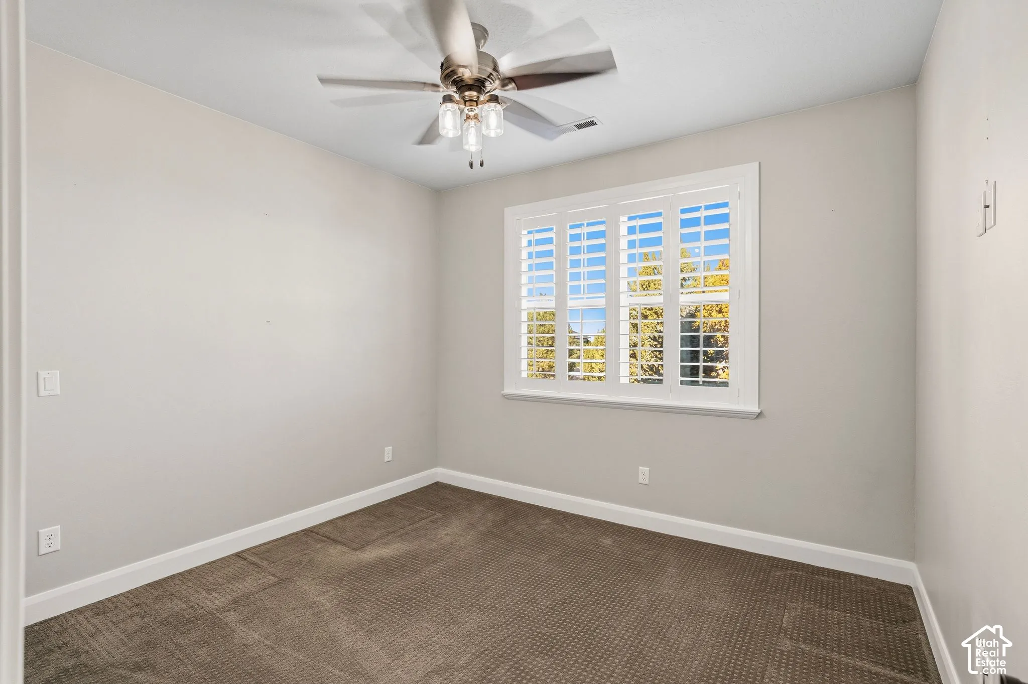 Window with plantation shutters and a ceiling fan with integrated lighting