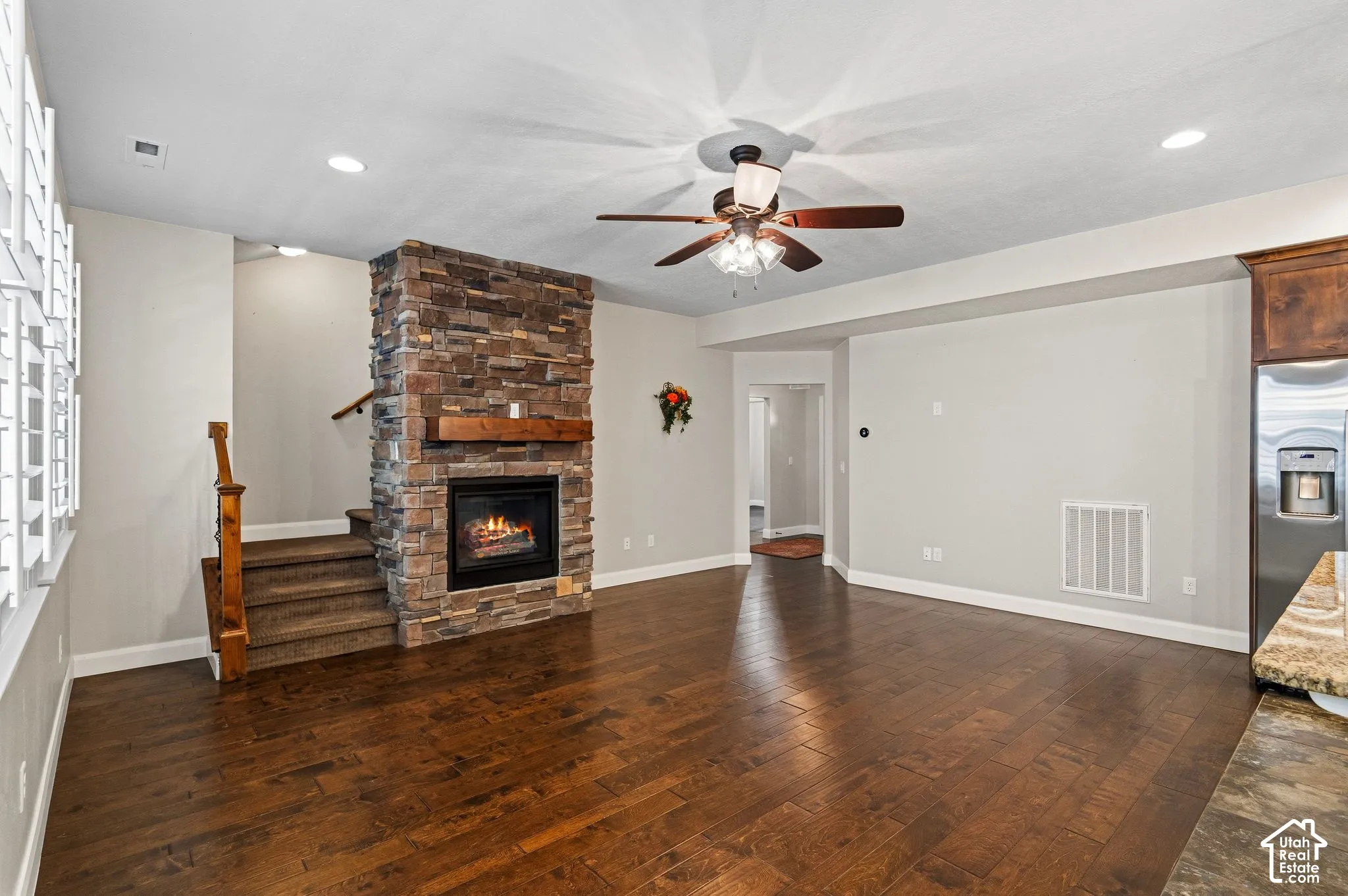 Stone-clad fireplace with a wood mantle, wood-finish flooring, and recessed ceiling lighting
